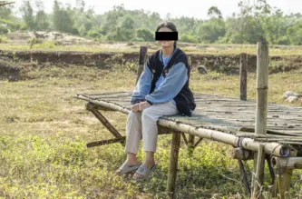 Vietnamilainen nuori nainen istuu ulkona laverin päällä.