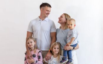 Perhe, jossa kaksi aikuista ja kolme lasta hymyilevät