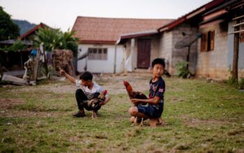 Kaksi aasialaista poikaa, molemmilla sylissään kanat.