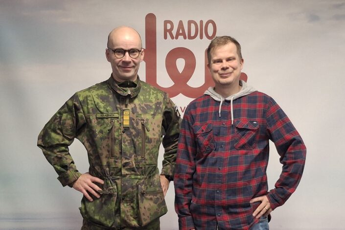Kenttärovasti Risto Kaakinen ja käsikirjoittaja-dramaturgi Ari-Pekka Lahti Radio Dein logon edessä.