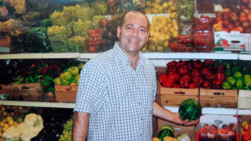 a_happy_man_holding_a_watermelon_in_store