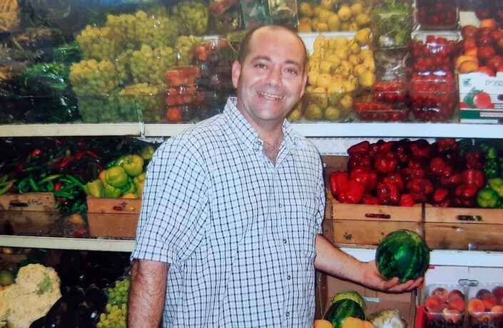 a_happy_man_holding_a_watermelon_in_store