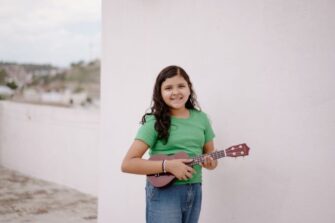 Alakouluikäinen tyttö soittaa ukulelea.