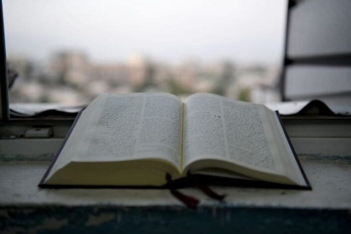 Avoin Raamattu ikkunalaudalla, taustalla kaupunkia.