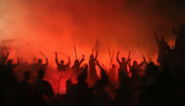 Punaista taustaa vasten mustia sotaisia hahmoja