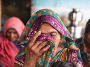 Huivipäinen nainen itkee ja rukoilee seurakunnassa