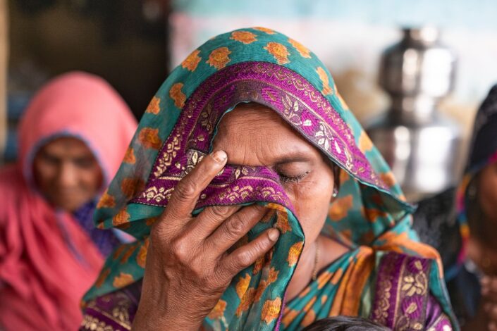 Huivipäinen nainen itkee ja rukoilee seurakunnassa