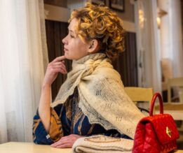 Nainen villashaalissa katsoo ulos ikkunasta