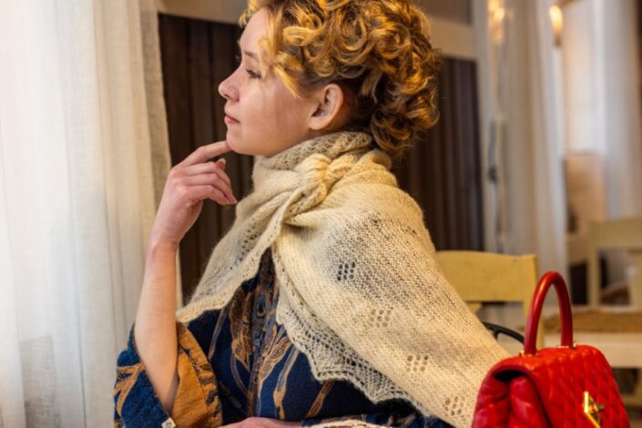 Nainen villashaalissa katsoo ulos ikkunasta