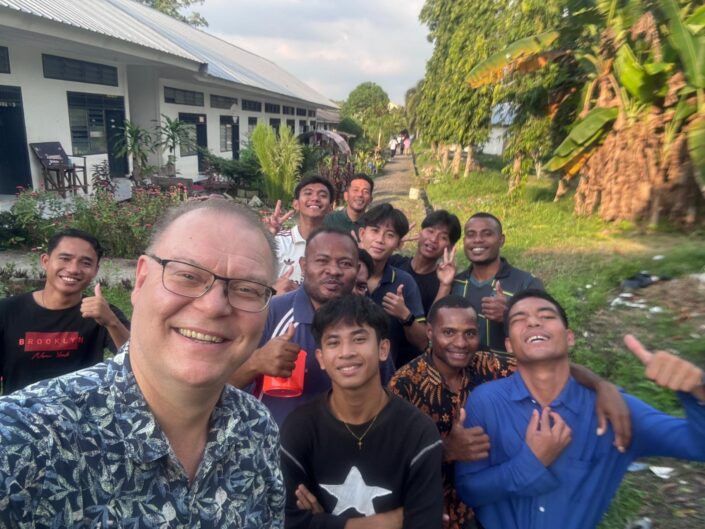 Hannu poseeraa selfiessä kymmenen etulinjan koulun oppilaan kanssa. 