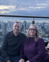 Pariskunta istuu terassilla taustallaan Bangkokin kaupunkisiluetti.