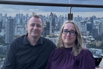 Pariskunta istuu terassilla taustallaan Bangkokin kaupunkisiluetti.