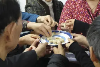 Ihmisiä ehtoollisella yhteisen lautasen äärellä.