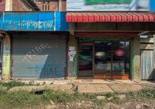 Seinässä autotallin kiinni oleva ovi sekä liikehuoneiston ikkunoita.