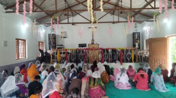 Intialaisia naisia kirkkosalissa, takaapäin kuvattuna.