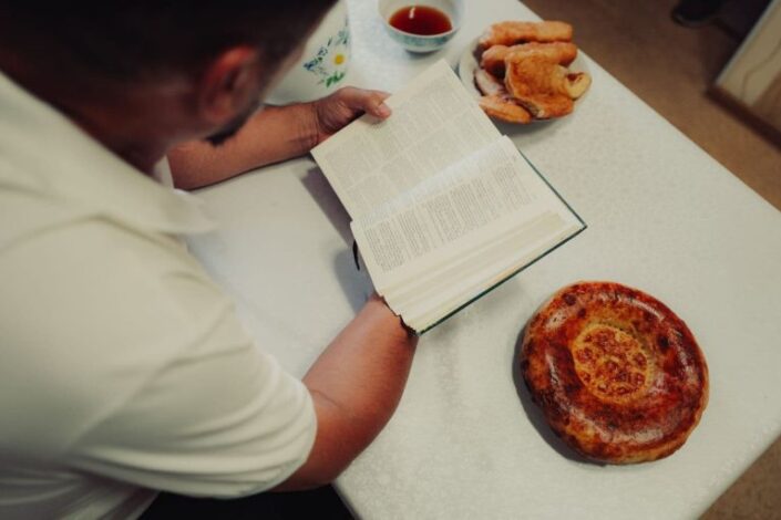 Mies lukee Raamattua pöydän ääressä.