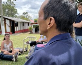 Mies kuvattuna takaviistosta. Hänen edessään istuu nuoria.