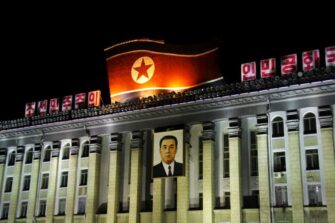 Suuri rakennus, jonka katolla on valtava Pohjois-Korean lippu ja etuseinällä roikkuu iso Kim Il Sungin muotokuva.