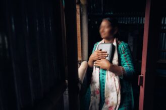 Nepalilainen nainen pitelee Raamattua rintaansa vasten.