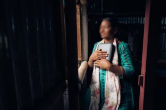 Nepalilainen nainen pitelee Raamattua rintaansa vasten.
