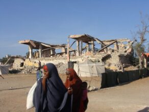 Somalinaisia sodassa tuhoutuneen rakennuksen ohi.