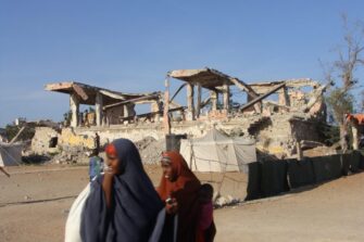 Somalinaisia sodassa tuhoutuneen rakennuksen ohi.
