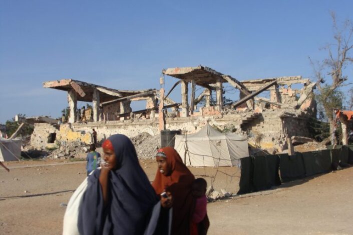 Somalinaisia sodassa tuhoutuneen rakennuksen ohi.