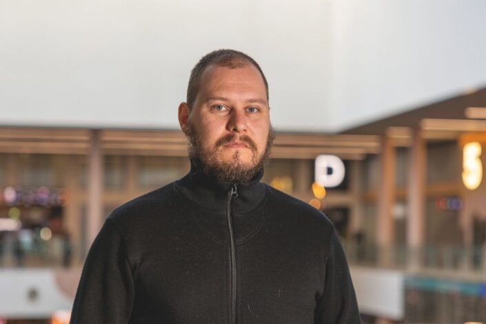 Mies kauppakeskuksessa katsoo suoraan kameraan