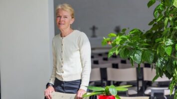Nainen kirkossa katsoo kameraan ja hymyilee