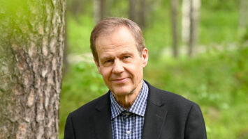 a-man-standing-outside-in-nature-and-smiling