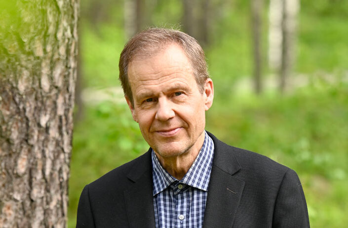 a-man-standing-outside-in-nature-and-smiling