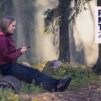Nainen metsässä lukee puhelimella Raamattua