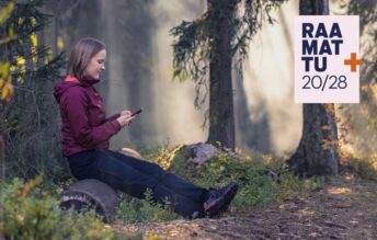 Nainen metsässä lukee puhelimella Raamattua