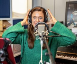 Nainen studiossa laittaa kuulokkeita päähänsä